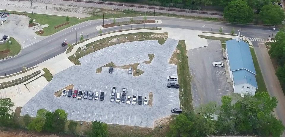 Aerial view of the paved Donahue lot with striped spaces and the blue-roofed building beside it